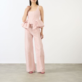 Model wearing Marques Almeida Pink Textured Brocade Boyfriend Jeans with wide-cut leg, styled with matching pink ruffled cami top and heels.