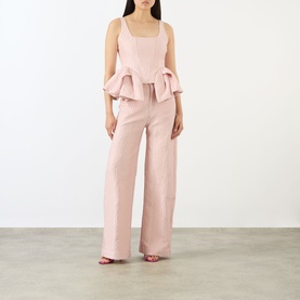 Model wearing Marques Almeida Pink Textured Brocade Boyfriend Jeans, wide-cut leg, styled with matching pink peplum top and pink heels