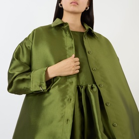 Model wearing Marques Almeida Heavy Fluid Shirt in khaki, heavyweight satin fabric, pointed collar, long sleeves, longline silhouette with dipped hem.