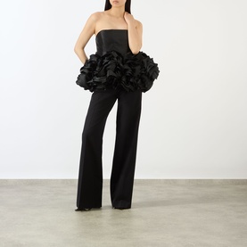 Model wearing Marques Almeida Ruffle Bustier Top in black with strapless fitted bodice and voluminous ruffled peplum hem, styled with wide-leg