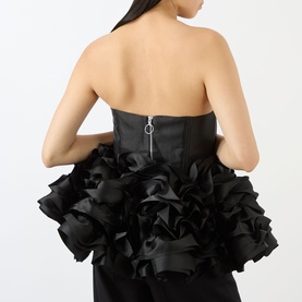 Model wearing Marques Almeida Ruffle Bustier Top in black, showing back zip fastening and voluminous ruffled ribbon peplum hem in heavy satin.