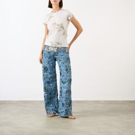 Model wearing Marques Almeida Sequin Embroidered Layered T-Shirt in White Nude with floral wide-leg jeans and flat sandals.