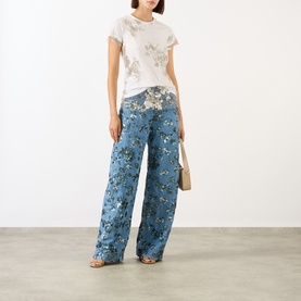Model wearing Marques Almeida White Nude Sequin Embroidered Layered T-Shirt with blue floral wide-leg trousers and nude sandals.