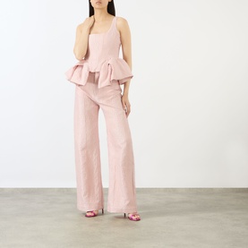 Model wearing Marques Almeida Pink Textured Brocade Peplum Corset Top with matching wide-leg trousers and pink heeled sandals.