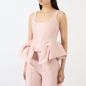 Model wearing Marques Almeida Textured Brocade Peplum Corset Top in pink, square neckline, sleeveless, with ruffled peplum hem. Styled with matching