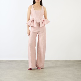 Model wearing Marques Almeida Pink Textured Brocade Peplum Corset Top with matching wide-leg trousers and red heeled sandals.