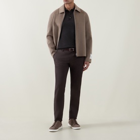 Model wearing Profuomo Dark Brown wool polo, styled with a taupe jacket, dark trousers and brown trainers.