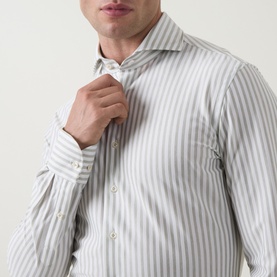 Model wearing Profuomo dark green stripe single cuff regular shirt, adjusting spread collar, long sleeves visible at cuff.