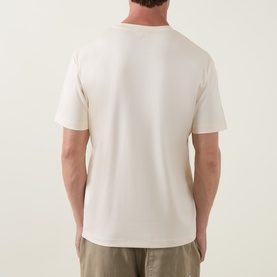 Model wearing Profuomo Solid Logo Pima T-Shirt in Raw White, rear view, short sleeves, crew neck, styled with khaki trousers.