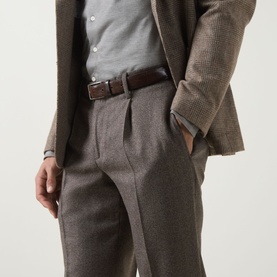 Model wearing Profuomo brown wool-blend trousers with pleated front, styled with a checked blazer and grey shirt.