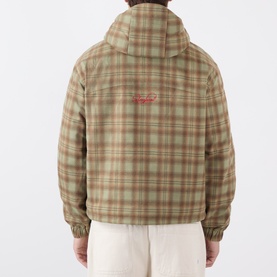 Model wearing Storefront Script Logo Flannel Utility Jacket in green check print, rear view showing hood and red script logo detail.