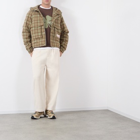Model wearing Storefront Script Logo Flannel Utility Jacket in green check, styled with cream trousers and graphic tee.