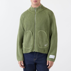 Model wearing Storefront Fisherman Script Logo Zip Sweater in olive, ribbed knit, funnel neck, front zip, patch pockets, styled with dark jeans.