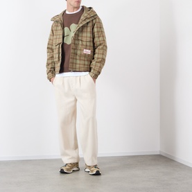 Model wearing Storefront brown cotton knitwear with green graphic, styled with tan plaid jacket and cream wide-leg trousers