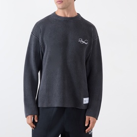 Model wearing Storefront Fisherman Script Logo Sweater in charcoal, featuring crew neck, ribbed knit texture and chest script logo detail.