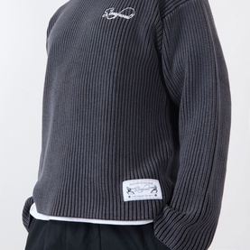 Model wearing Storefront Fisherman Script Logo Sweater in charcoal, ribbed knit, crew neck, chest script logo, styled over white layer with black