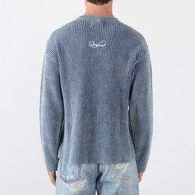 Model wearing Storefront blue ribbed cotton knit sweater, back view with logo embroidery, styled with distressed jeans