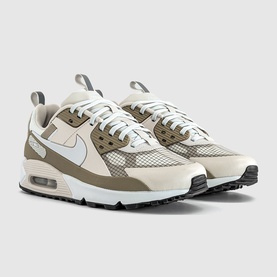 Nike Air Max 90 trainers in light bone and off-white with olive overlays, mesh detailing, and black rubber sole