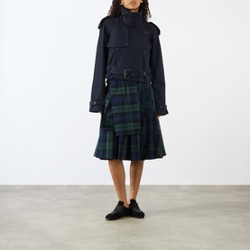 Model wearing JW Anderson navy cotton jacket with belted waist, styled with green tartan kilt skirt and black shoes