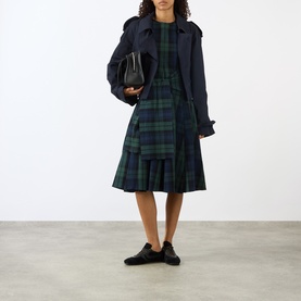 Model wearing JW Anderson navy cotton jacket, styled with green tartan dress and black bag and shoes.