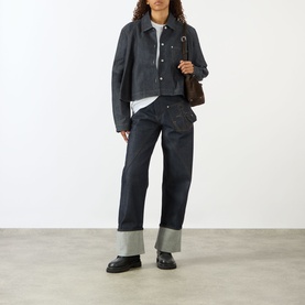 Model wearing JW Anderson Twisted Wide Leg Trousers in indigo, wide leg silhouette with turned-up hem, styled with a denim jacket and loafers.