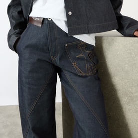 Model wearing JW Anderson Twisted Wide Leg Trousers in indigo, featuring anchor logo stitching on pocket, wide leg fit and contrast stitching detail.