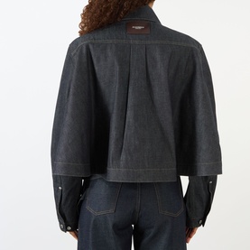 Model wearing JW Anderson Flare Hem Denim Shirt in indigo, rear view showing back pleat, logo patch, and flared silhouette, styled with dark denim