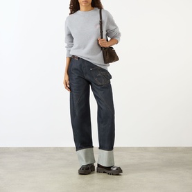 Model wearing JW Anderson Anchor Logo Sweatshirt in Mid Grey Melange, crew neck, long sleeves, styled with dark indigo jeans and chunky loafers
