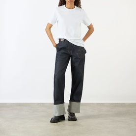 Model wearing JW Anderson Anchor Logo T-Shirt in White, styled with dark indigo wide-leg cuffed jeans and black loafers.