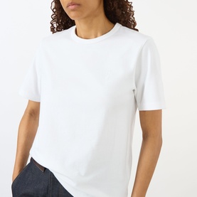 Model wearing JW Anderson Anchor Logo T-Shirt in White 001, round neck, short sleeves, paired with dark denim jeans.