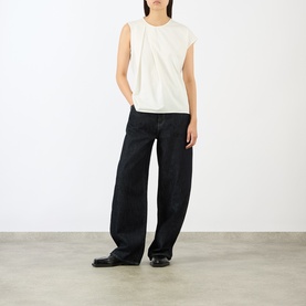 Model wearing JW Anderson ivory cotton sleeveless top with pleat detail, styled with wide-leg black trousers and black loafers.