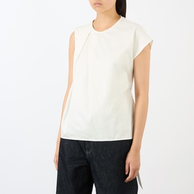 Model wearing JW Anderson ivory cotton top with cap sleeves and asymmetric front seam detail, styled with dark denim trousers