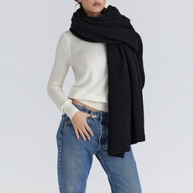 Model wearing House of CB ivory knit scarf draped over shoulders, styled with cream jumper and blue jeans