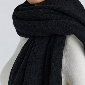 Model with House of CB scarf styled over ivory knit top, shown in oversized wrap with textured knit finish in black