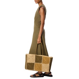 Model carrying Whistles bag in multi-tone beaded checkerboard design with top handles, styled with olive maxi dress and sandals
