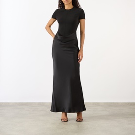 Model wearing Rotate black maxi dress with short-sleeve fitted top bodice and satin-finish skirt, styled with black heeled sandals
