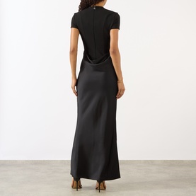 Model wearing Rotate black maxi dress, rear view showing cowl back detail and satin skirt with short-sleeve fitted top layer