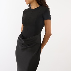 Model wearing Rotate black dress with short sleeves, panelled bodice and draped satin-finish skirt detail at hip.