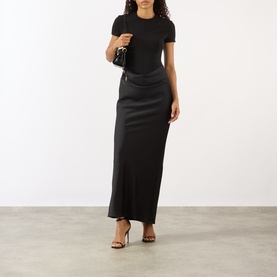 Model wearing Rotate black maxi dress with short sleeves, styled with black strappy heels and small black bag.