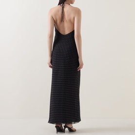 Model wearing Rotate black maxi dress, rear view showing low open back, halterneck tie, and all-over dot pattern on sheer fabric.