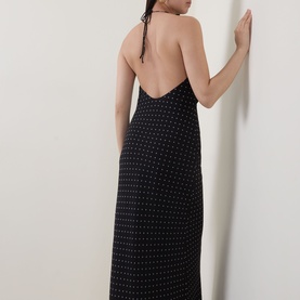 Model wearing Rotate black polka dot halterneck maxi dress with open back, shown from behind