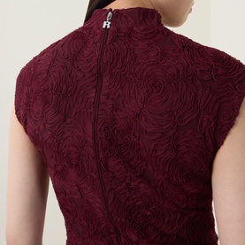 Model wearing Rotate Dress in Decadent Chocolate, back view showing textured rosette fabric, zip fastening, and high neck detail.