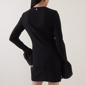 Model wearing Rotate black mini dress, back view, long sleeves with fluted cuffs and fitted silhouette