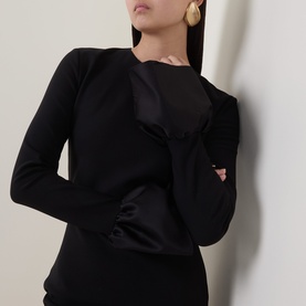 Model wearing Rotate black dress with structured bodice detail, styled with gold drop earrings. Long sleeves, close-fitting silhouette.