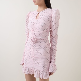 Model wearing Rotate barely pink dress with polka dot print, keyhole neckline, ruched long sleeves, floral waist detail and frill hem