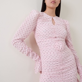 Model wearing Rotate barely pink polka dot ruched mini dress with keyhole neckline, long sleeves and ruffled cuffs