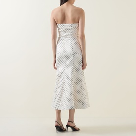 Model wearing Rotate Dress in Egret polka dot print, rear view, midi length with fluted hem, styled with black heeled sandals
