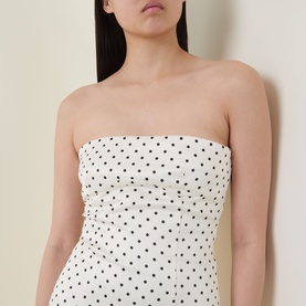 Model wearing Rotate strapless polka dot dress in Egret with black dot AOP print, fitted bodice