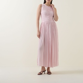 Model wearing Rotate barely pink sleeveless maxi dress with ruched bodice and pleated skirt, styled with brown heeled sandals