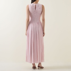 Model wearing Rotate barely pink floral midi dress, sleeveless with smocked bodice and pleated skirt, keyhole back detail, styled with brown heels.